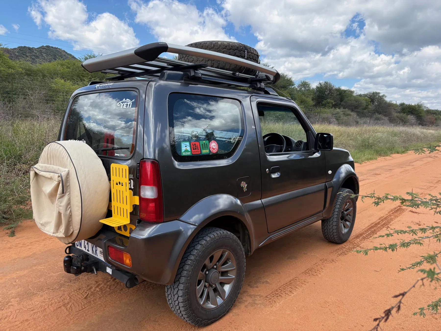 Atlas, a 2017 Suzuki Jimny Gen 3, on a dirt road with roof basket and rear-door equipment