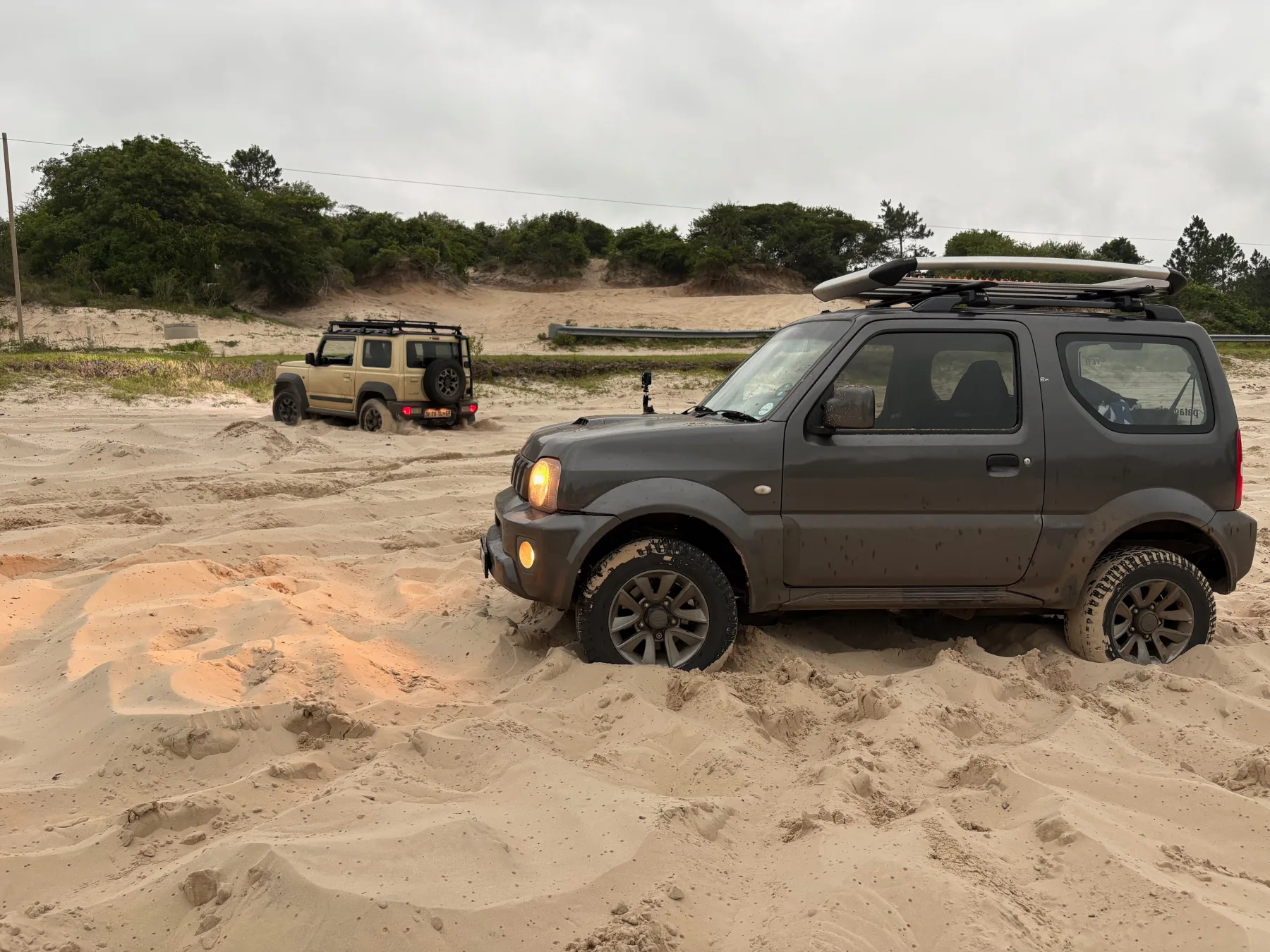 Gen 3 and Gen 4 Suzuki Jimnys driving on sand